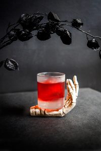 The Devil's Negroni with black glitter roses and a skeleton hand