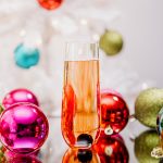 Haute Holiday Sparkling Wine Cocktail with ornaments and a Christmas tree
