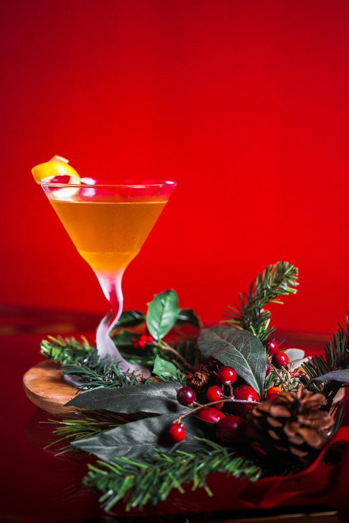 Sugar and Spice Cocktail with a lemon twist garnish and holiday greenery.
