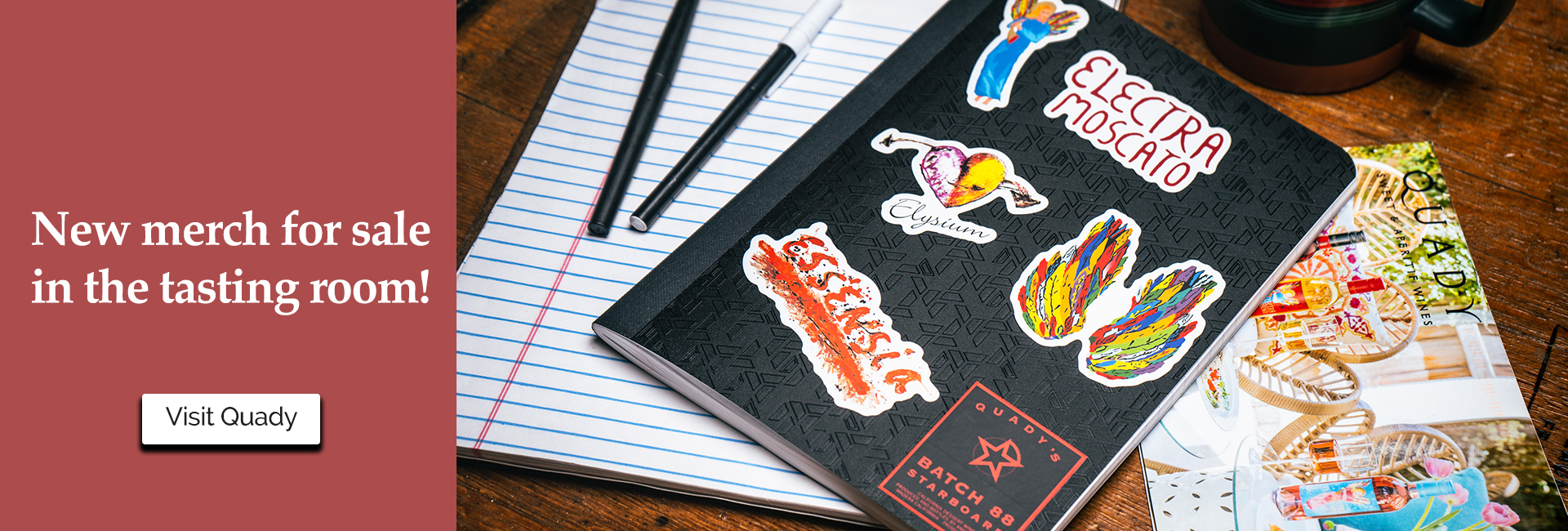 New merch for sale in the tasting room! visit quady. Photo of notebook with various quady stickers