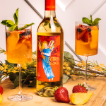 Two glasses of Summer Sangria with a bottle of Electra Moscato and peaches and strawberries