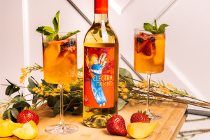 Two glasses of Summer Sangria with a bottle of Electra Moscato and peaches and strawberries