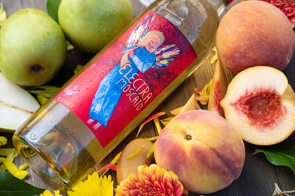 Electra Moscato surrounded by fresh peaches and pears.