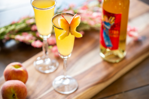 Electra Bellini with a peach butterfly garnish and a bottle of Electra Moscato