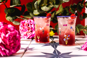 Raspberry Lemonade Moscato Spritzers with raspberry garnishes and flowers in the background.