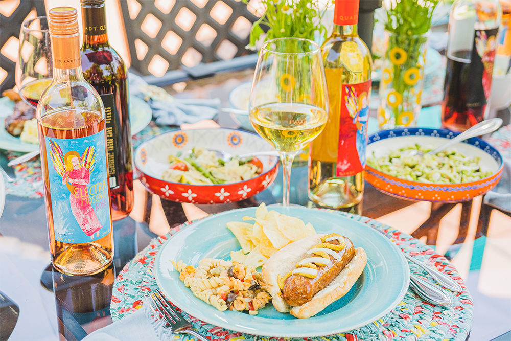 A hotdog and chips with a bottle of Electra Rosé and Electra