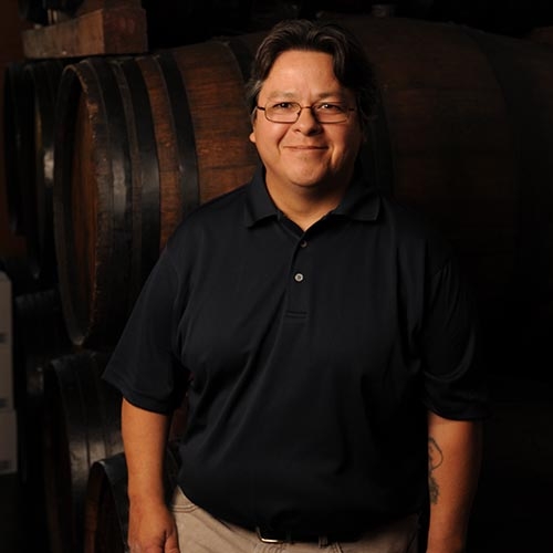 Dan Mejia in front of wine barrels at Quady Winery in Madera, California.